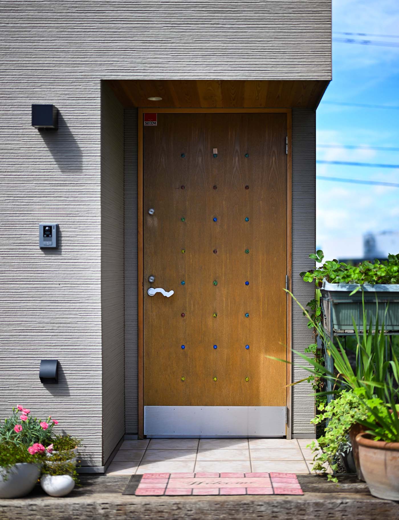 ビー玉があしらわれた木製の玄関ドアは、この住宅のためにデザイン・製作したオリジナル