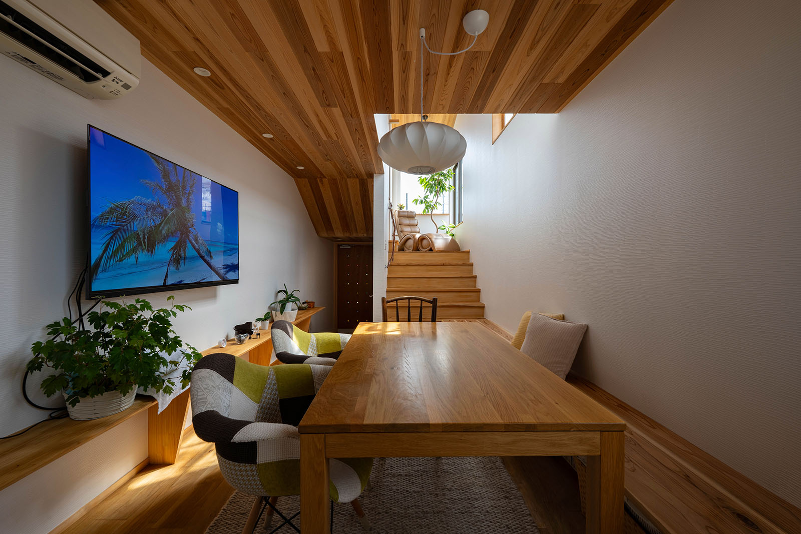 キッチンから玄関方向を望む。木の温もりたっぷりのリビング・ダイニングは、壁沿いにベンチを造作して省スペース化