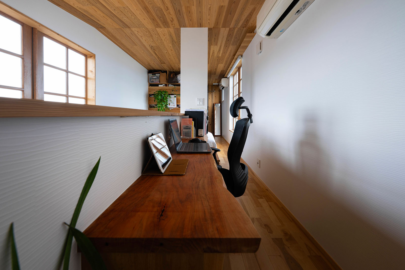 廊下の一部を活用したワークスペース用に一枚板でカウンターを造作。吹き抜け越しの窓からは夜景を楽しめる